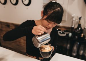 woman pouring cream on mug inside bar